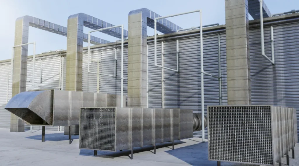 Un grand bâtiment industriel avec plusieurs grands climatiseurs en métal sur le toit.
