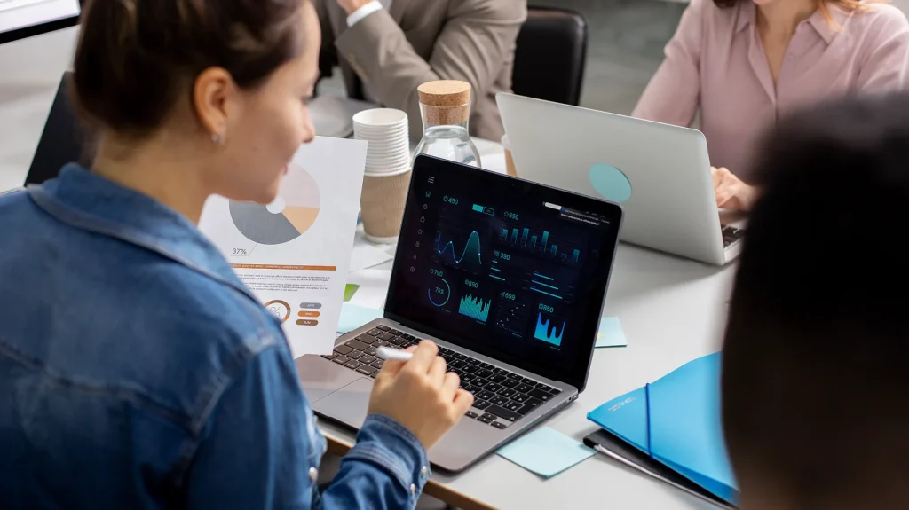 Décuplez la performance de vos projets avec un diagnostic machine de pointe : l'approche Groupe AVA 5 Un groupe de personnes assises autour d'une table avec des ordinateurs portables, discutant d'une machine de diagnostic.
