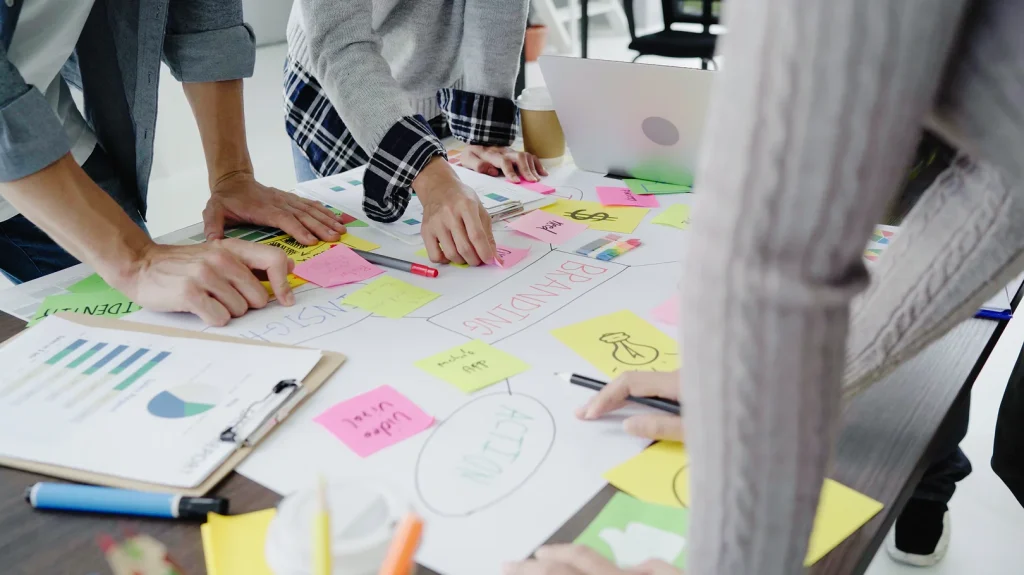 Des personnes collaborent sur un projet, utilisant des notes autocollantes pour la gestion des actifs.