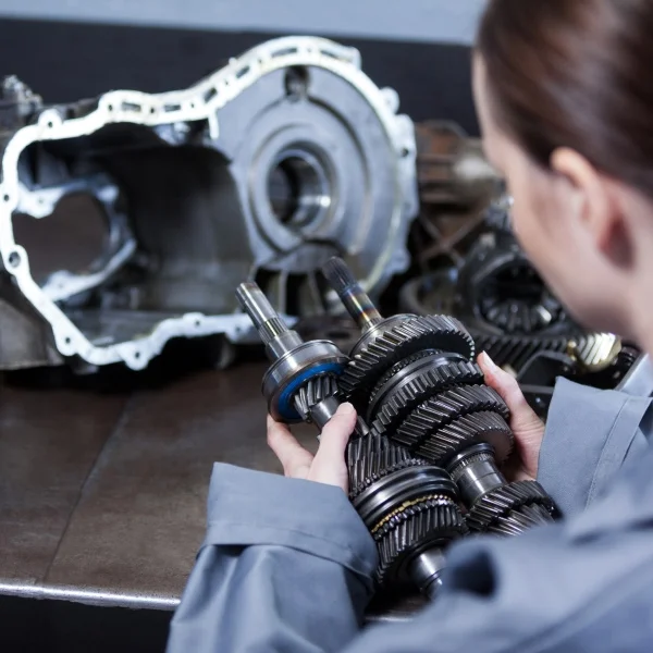 Moteur WEG : performance et efficacité pour l’industrie 2 Une mécanicienne examine de près les engrenages d'une boîte de vitesses dans un atelier industriel.